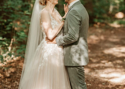 Braut berührt Bräutigam liebevoll im Wald